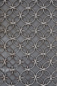 Vintage iron door frame with circles pattern detail and stained glass background.