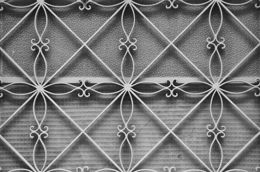 Antique metal door frame with geometric floral pattern and stained glass texture.