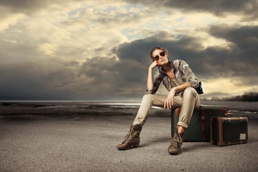 Beautiful young woman photographer sitting on a suitcase