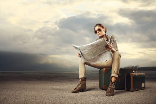 Beautiful young woman sitting on a suitcase