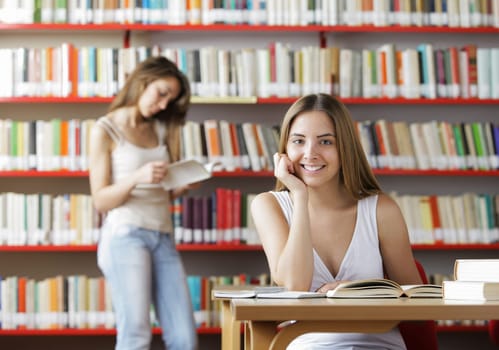 Portrait of a smiling student in a library. Young woman reading a book on background