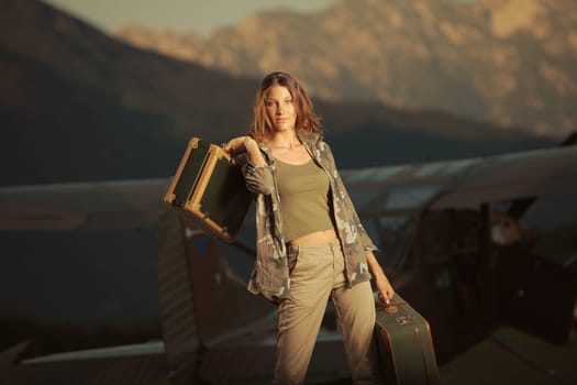 Young beautiful woman with suitcases ready to go by plane at sunset
