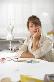 Portrait of attractive female fashion designer sitting at office desk