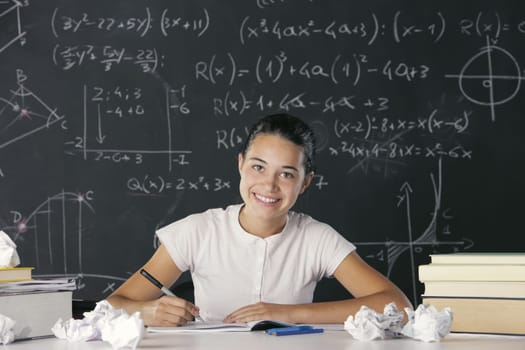 Young student writes in the notebook, in the background a blackboard full of math formulas