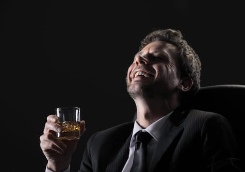 Happy middle aged man drinking whiskey against black background