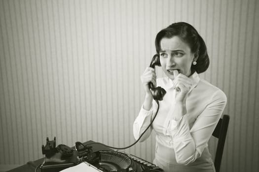 Woman embarrassed talking on phone at her desk