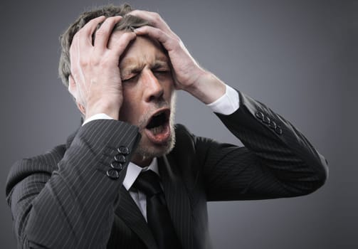 A screaming worried, depressed, and stressed out businessman holds his head