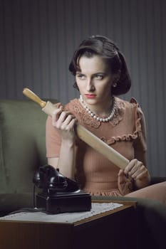 Angry wife waiting for her husband with a rolling pin in hand