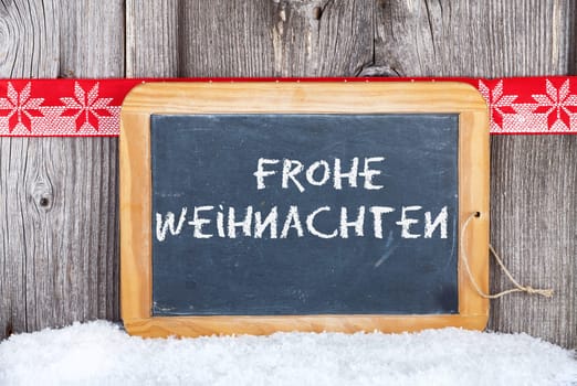 Christmas greeting card with text on slate on a rustic wooden background