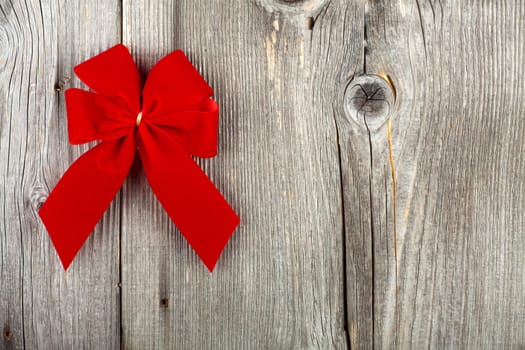 Decorative Christmas background with text space and red gift bow on rustic wooden background