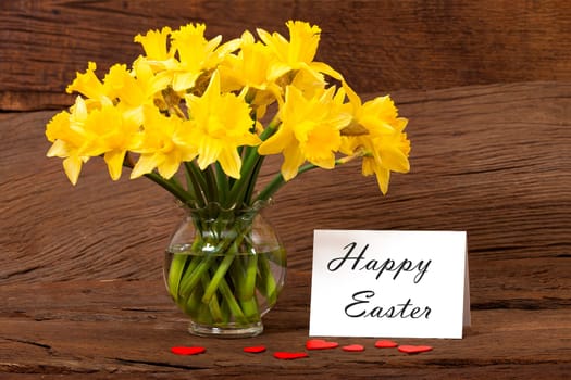 Easter Greetings on a white Card with Daffodils Flowers on a old wooden Background
