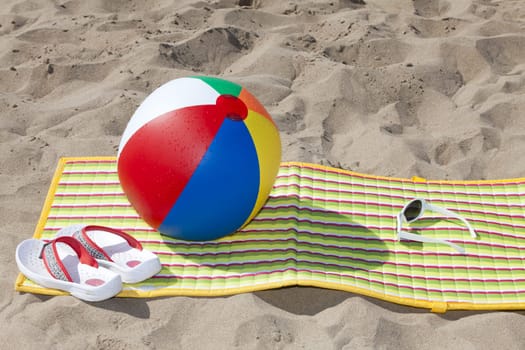 Beach mat with flip flopsSunglasses and a buten water polo