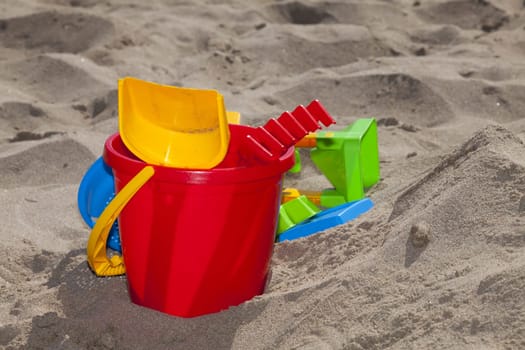 Red bucket with beach toy on the sandy beach