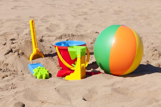 Colorful toys and a water polo lie on the beach
