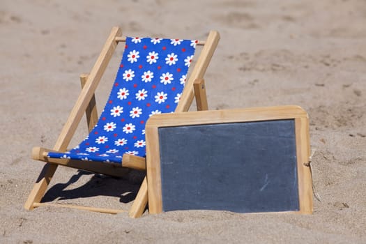 Beach lounger and a slate as advertising space stand on the beach