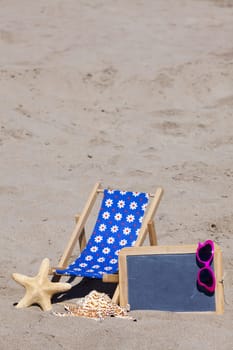 Beach lounger and a slate with sunglasses as advertising space stand on the beach