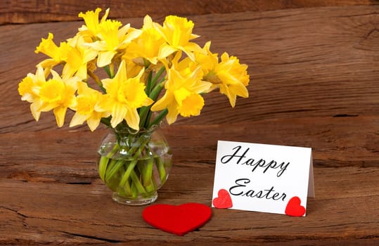 Easter Greetings on a white Card with Daffodils Flowers on a old wooden Background