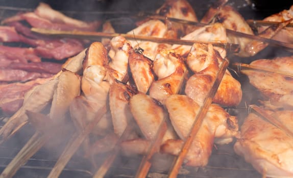 fried chicken on skewers over charcoal in a smoke