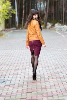 Slender girl goes through the autumn alley and turns around, smiles
