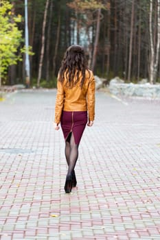 Skinny girl goes through the alley in the forest