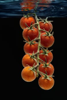 Cherry tomatoes in water. Black background