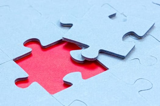 Jigsaw with one piece missing revealing red background