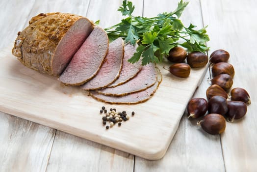 Sliced roast beef with some ingredients on the table of the kitchen