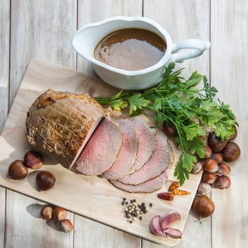 Sliced roast beef with some ingredients on the table of the kitchen