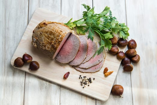 Sliced roast beef with some ingredients on the table of the kitchen