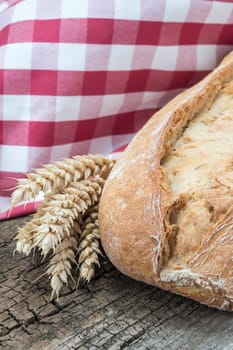 Wheat bread with ears on a cutting board isolated on a white background