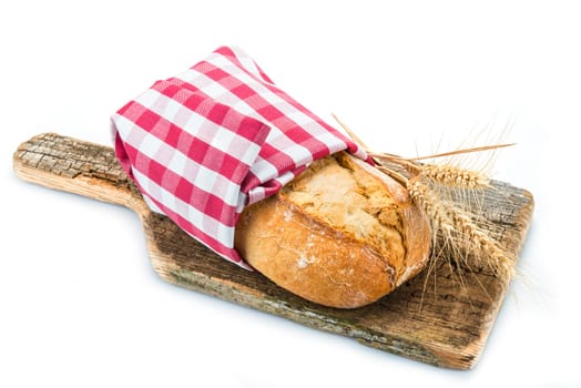 Wheat bread with ears on a cutting board isolated on a white background