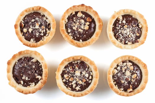 Six bite sized chocolate tarts with chopped nuts.