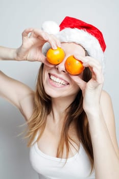 Funny girl in a christmas hat with mandarins
