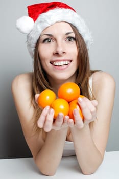 Funny girl in a christmas hat with mandarins