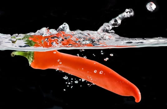 Close up on Red pepper splashing into water isolated on black