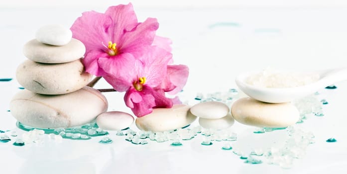 Spa stones sea salt and pink flower on white