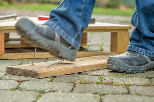 Worker with safety shoes steps into a nail