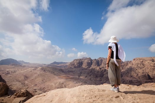 Woman is admiring a view of Jordanian desert while hiking in Petra.