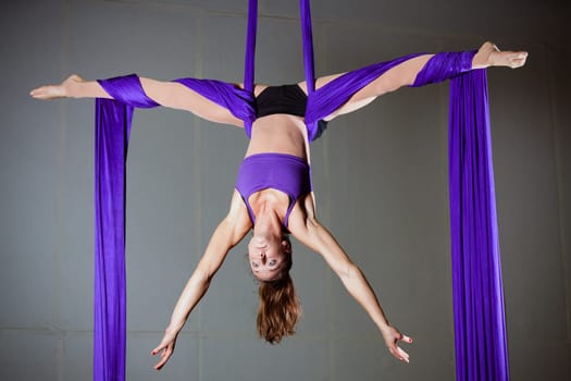 Beautiful woman gymnast performing aerial exercises