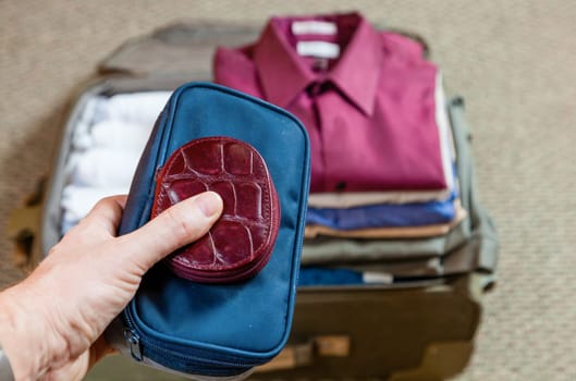 A man is packing suitcase at home for a business trip