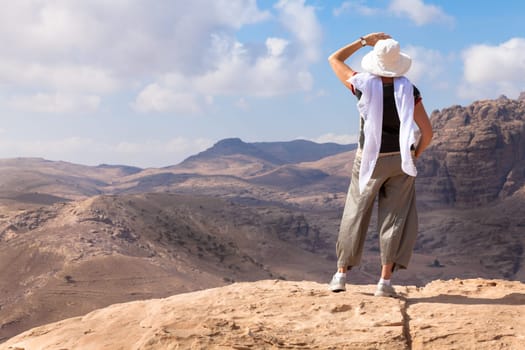 Woman is admiring a view of Jordanian desert while hiking in Petra.