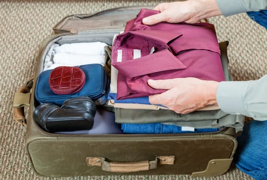 A man is packing suitcase at home for a business trip
