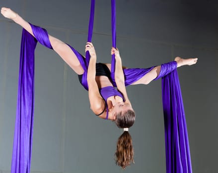 Beautiful woman gymnast performing aerial exercises