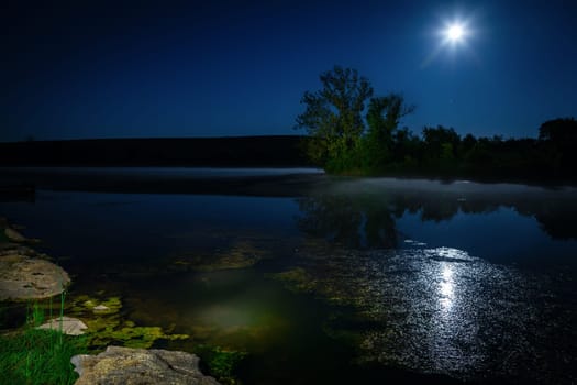 Scenic nighttime landscape with full moon rising over the lake