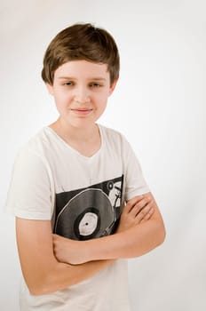 Upper body portrait of a young male teenager in a T-shirt and crossed arms in front of a white background smiling at the camera from an elevated view