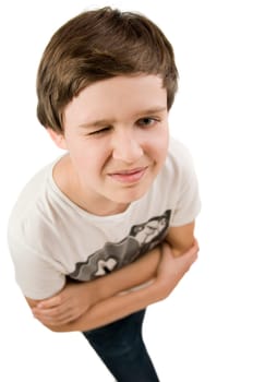 Upper body portrait of a young male teenager in a T-shirt and crossed arms in front of a white background squinting at the camera from elevated view