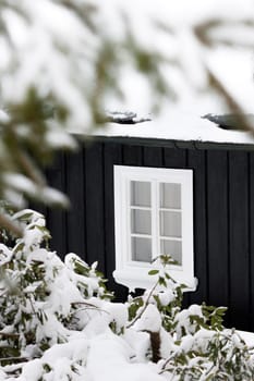 Detail Of A Black Wooden Cottage In Winter Time With One White Window