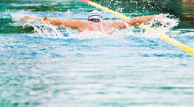 Swimmer performing the butterfly stroke  in olimpic basin