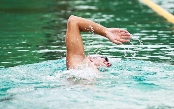 Young man swimming the front crawl in a pool