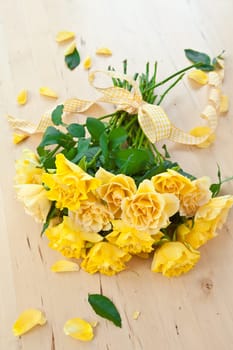 Fresh yellow roses with bow on wooden background